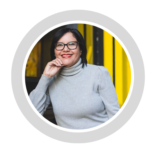 Dr. Sandra Ralat poses with her hand on her chin, wearing a gray sweater