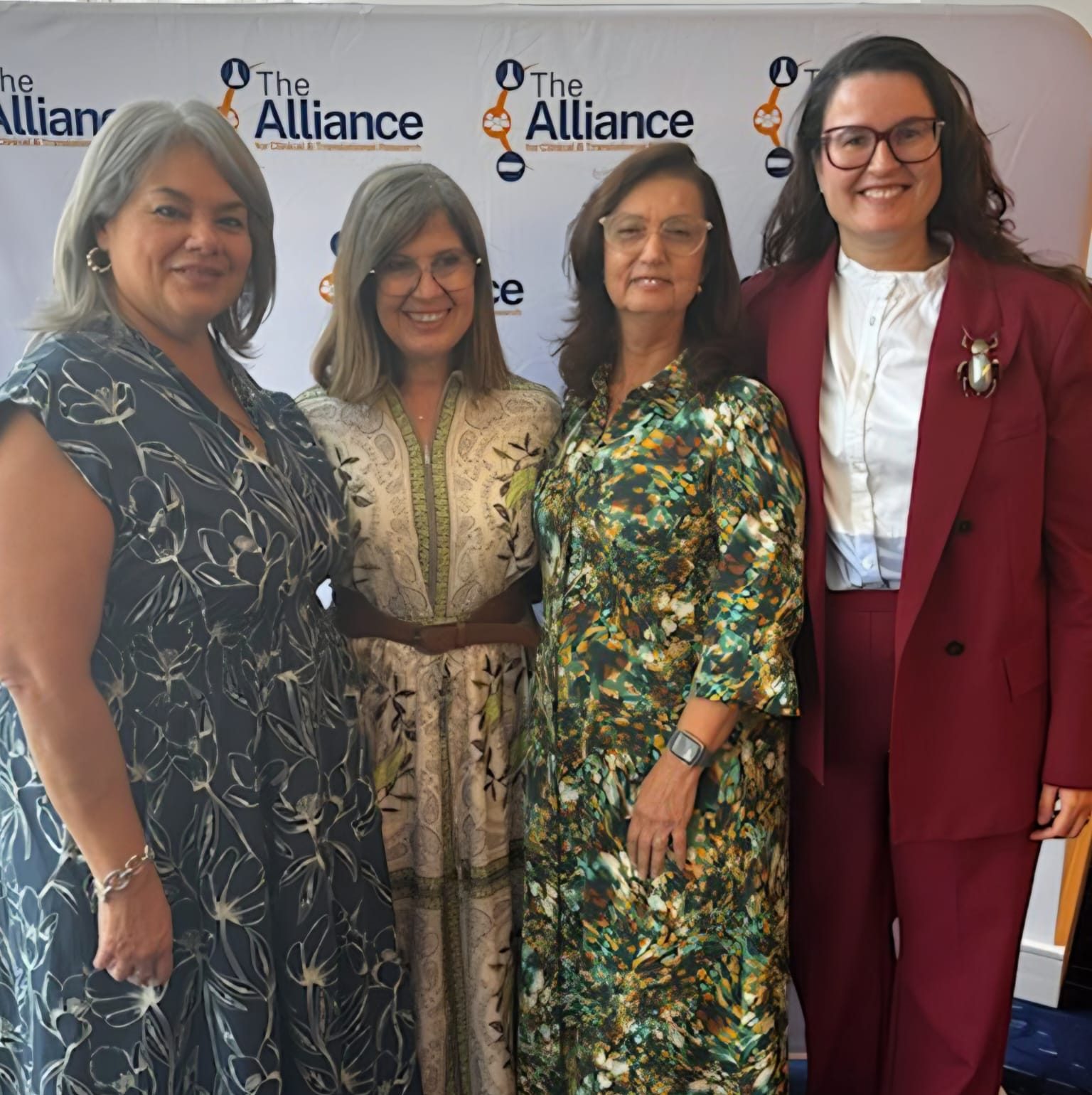 Alliance team members posing in front of branded backdrop